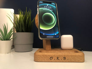 Solid oak rectangular stand with vertical tower to hold MagSafe charger. Lightning cable protrudes on right to hold AirPods. Groove on front to hold bits. Curved top profile, micro suction feet to hold to flat surface. Personalisation shows on front face.