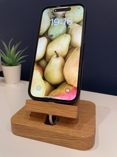 Solid oak desktop charging dock, shown with wire fixed in place and phone sits at an angle.  Adheres to desk with non marking suction. 